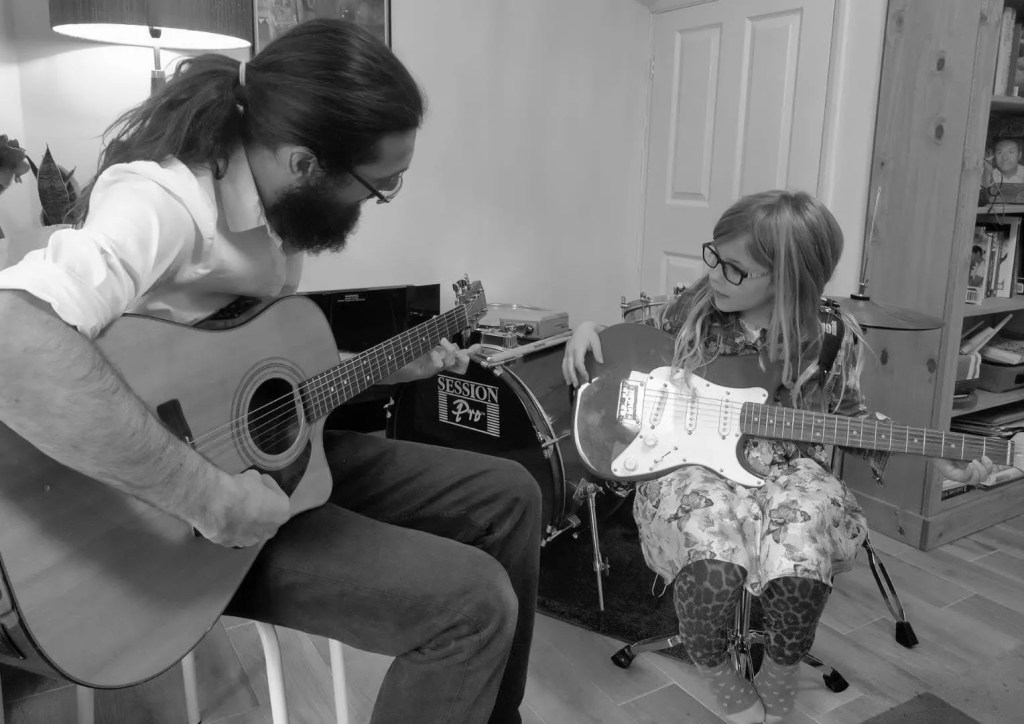 Guitar bass teacher Adam Frost with a young student during a lesson.
